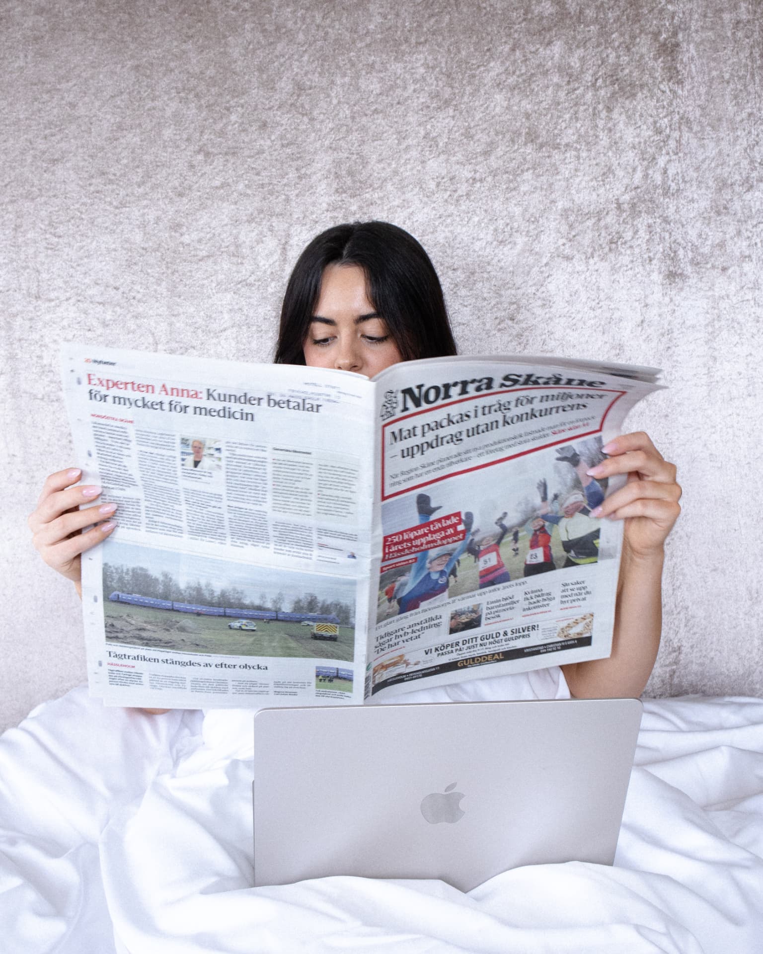 Kvinna läser tidningen i hotellsängen